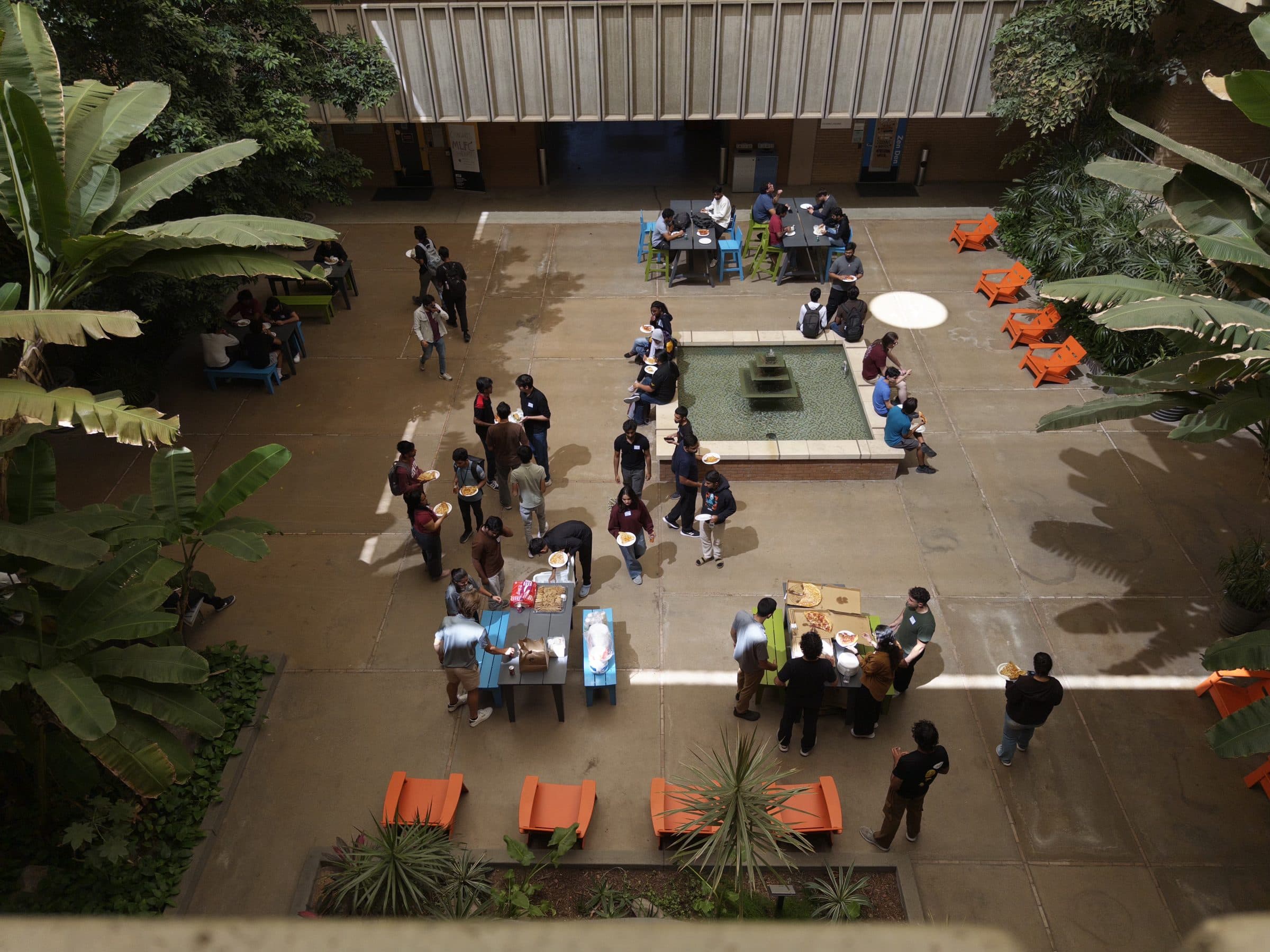 Looking down into a planted courtyard where students eat around a fountain and picnic tables during the lunch laid on for the 2026 ASU Energy Hackathon.
